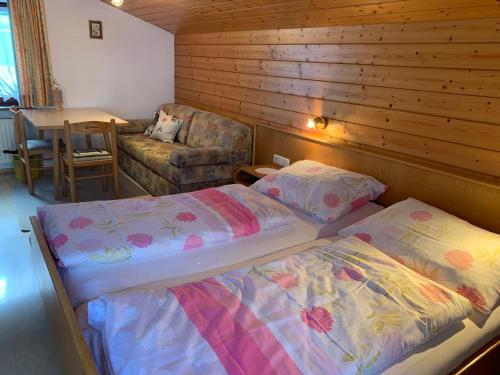 a bedroom with two beds and a chair and a table at Haus Aurelia in Au im Bregenzerwald