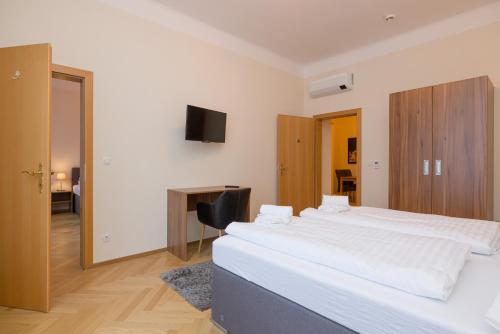 a bedroom with two beds and a desk and a television at Vienna Stay Apartments Schönbrunn in Vienna