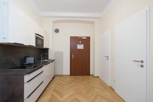 a kitchen with white cabinets and a wooden floor at Vienna Stay Apartments Schönbrunn in Vienna