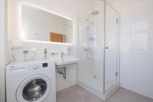 a white bathroom with a washing machine and a shower at Vienna Stay Apartments Schönbrunn in Vienna
