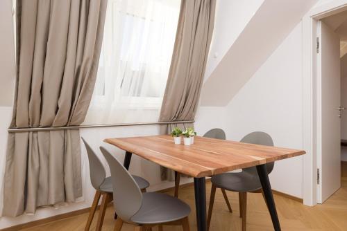 uma sala de jantar com uma mesa de madeira e cadeiras em Vienna Stay Apartments Schönbrunn em Viena