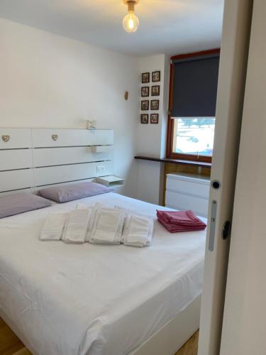 a bedroom with a bed with white sheets and a window at New Bilocale Centro vista Cervino in Breuil-Cervinia