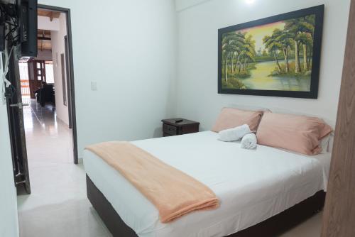 1 dormitorio con 1 cama blanca y una pintura en la pared en El EmAnJe 1, en Jardín