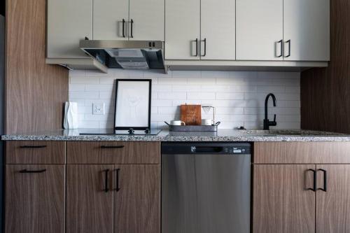 a kitchen with white cabinets and a dishwasher at Yugo Guest Suites in Urbana