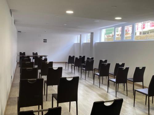 a room with black chairs and a white wall at Oca Playa de Foz Hotel & Spa in Foz