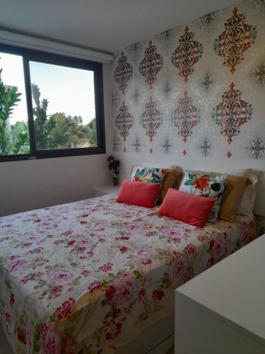 um quarto com uma cama grande e almofadas vermelhas em Aconchegante Flat em condomínio na beira mar de Muro Alto - Malawi Beach Resort em Porto de Galinhas