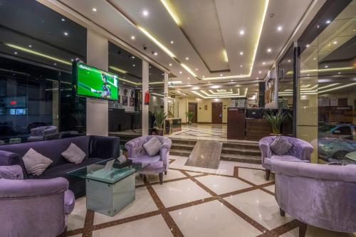 un vestíbulo con sofás púrpura y TV. en Al Muhaidb Hotel Apartments 24 en Riad
