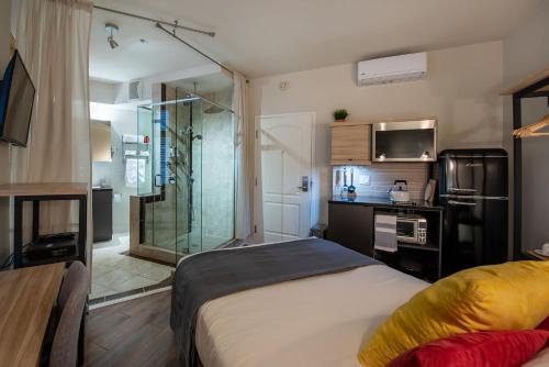 a bedroom with a bed and a glass shower at Appart-Hôtel Le Vincent in Quebec City