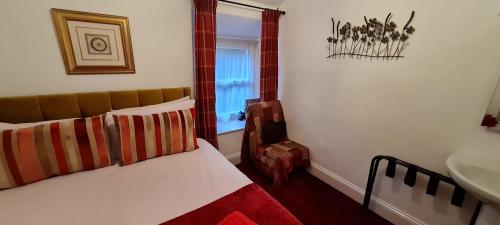 a bedroom with a bed and a chair and a window at Holly Cottages in Bowness-on-Windermere