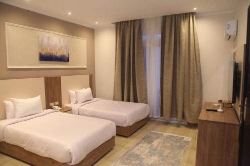 a hotel room with two beds and a television at Jewel Assiut Hotel in Asyut