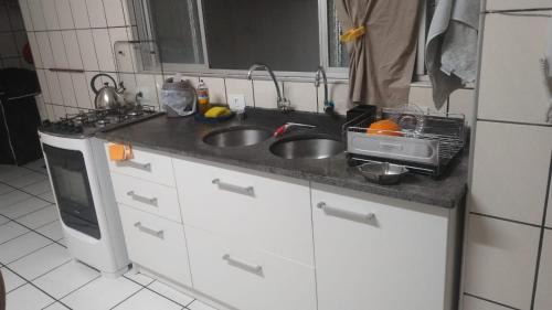 a kitchen counter with two sinks and a microwave at Apartamento 3 quartos e 3 sacadas de frente para o mar com visão panorâmica de toda praia de Itapema in Itapema