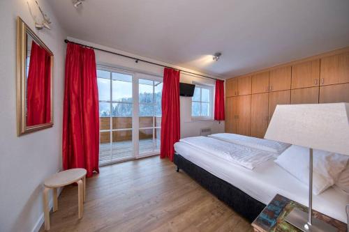 薩爾巴赫－欣特爾格勒姆的住宿－Holidayhome with Sauna Genieten in Saalbach Top E2，一间卧室配有一张带红色窗帘的床和一扇窗户