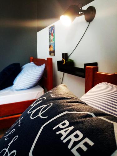 a bedroom with two beds and a lamp on the wall at Casa Arembepe in Camaçari