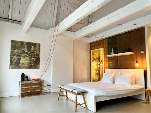 1 dormitorio con cama blanca y banco en B&B Bierbrouwerij het Klavertje, en Dokkum