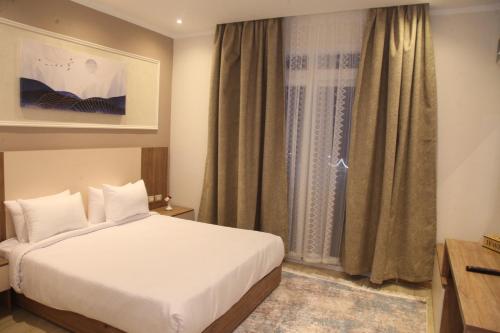 a bedroom with a white bed and a window at Jewel Assiut Hotel in Asyut
