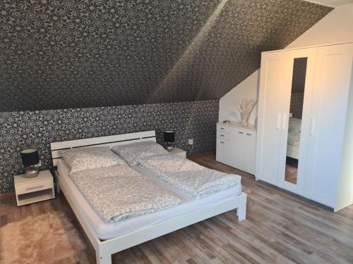 a bedroom with a white bed and a wall at Ferienwohnung Lilith in Brilon
