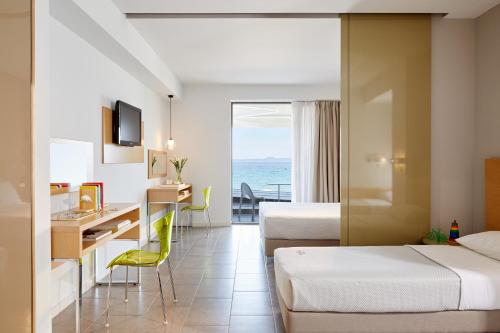 a hotel room with two beds and a desk at Margarita Sea Side Hotel in Kallithea Halkidikis