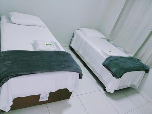 duas camas sentadas uma ao lado da outra num quarto em Hotel Pousada Bueno's em Francisco Beltrão