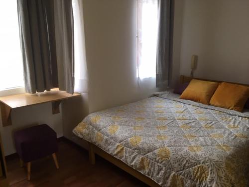 a bedroom with a bed and a chair and two windows at Mini Studio cerca de playa in Viña del Mar
