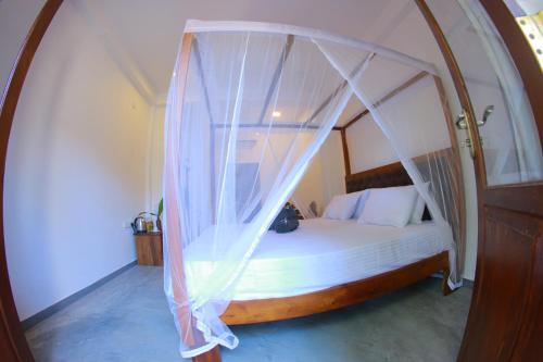 a bedroom with a bed with a canopy at Monkey Beach in Dickwella