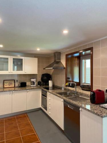 a kitchen with white cabinets and granite counter tops at Casa de Alventela - Countryside House in Paredes de Viadores