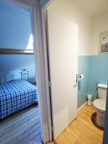 a bathroom with a toilet and a bed in a room at Le Clos de la Borde, Chambre bleue in Arches