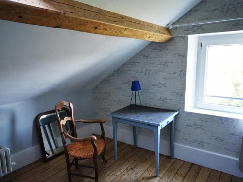 a table and a chair in a room with a window at Le Clos de la Borde, Chambre bleue in Arches