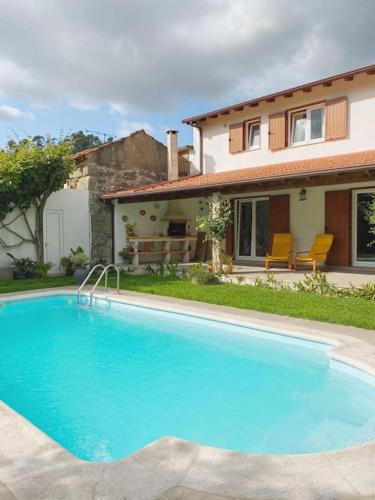 a large blue swimming pool in front of a house at Casa de Alventela - Countryside House in Paredes de Viadores