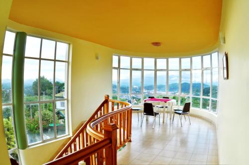 a dining room with a table and chairs and large windows at Kandyan View Holiday Bungalow free pickup from kandy in Kandy