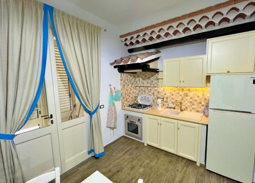 La cuisine est équipée de placards blancs et d'un réfrigérateur blanc. dans l'établissement Sa Domo de Tzia Elene, à Irgoli