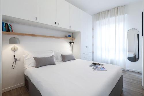 Un dormitorio blanco con una gran cama blanca y una ventana en Contempora Apartments - Casale 3, en Milán