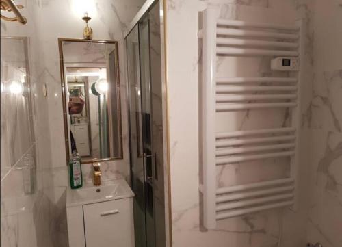 a white bathroom with a sink and a mirror at Clair de plage in Frontignan