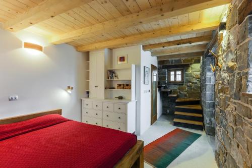 a bedroom with a red bed and a stone wall at Mountain Lodge Istria, Tiny house in Roč