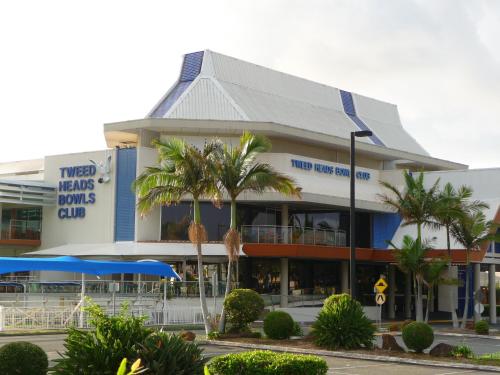 a building with palm trees in front of it at Blue Pelican Motel in Tweed Heads