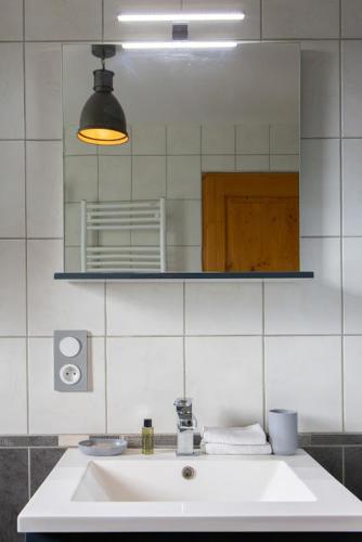 a bathroom with a white sink and a mirror at Gîtes de l'Orée du Bois - Boussières in Boussières