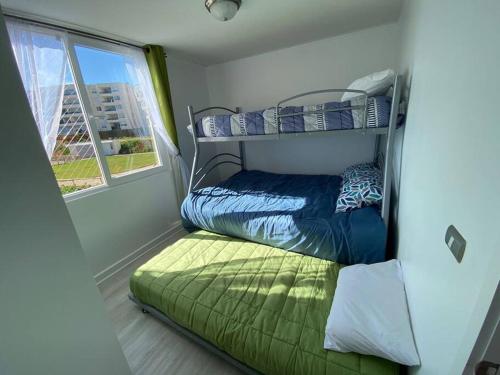 een kleine kamer met een stapelbed en een raam bij Hermoso Departamento Familiar Punta Puyai in Papudo