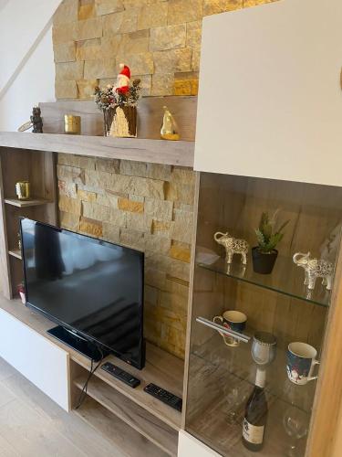 a television in a living room with a stone fireplace at Milmari Apartman N92 Kopaonik in Kopaonik