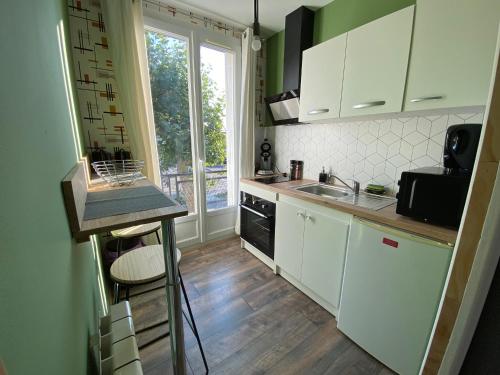 a kitchen with white cabinets and a sink and a window at L’havrais détente in Le Havre