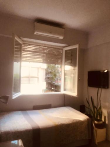 a bedroom with a bed and a window with a blind at Monoambiente in Buenos Aires
