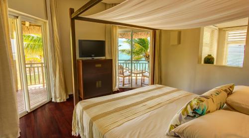 a bedroom with a bed and a television and a balcony at Solana Beach Mauritius - Adults Only in Belle Mare