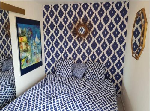 a bedroom with a blue and white bed and a wall at Clair de plage in Frontignan