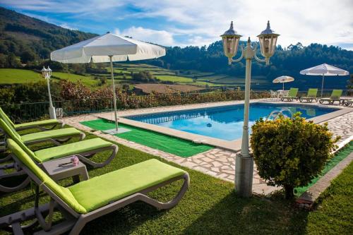 a pool with chairs and an umbrella and a couple of umbrellas at Casa dos Leões- Aldeia dos 4 abades in Ponte de Lima