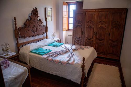 a bedroom with a bed and a large wooden cabinet at Casa dos Leões- Aldeia dos 4 abades in Ponte de Lima