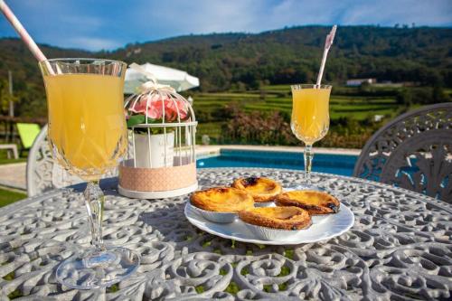 a table with two glasses of orange juice and some pastries at Casa dos Leões- Aldeia dos 4 abades in Ponte de Lima