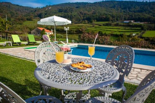 a table with a plate of food and two drinks at Casa dos Leões- Aldeia dos 4 abades in Ponte de Lima