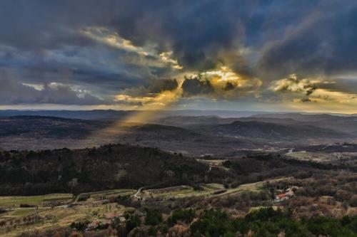 a stormy sky with the sun shining through the clouds at Mountain Lodge Istria, Stone Lodge I in Roč