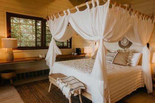 a bed with a canopy on top of it at Tranquilseas Eco Lodge & Dive Center in Sandy Bay