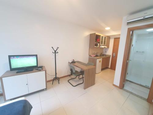 a living room with a tv and a desk with a computer at Flat Saint Moritz Express By Rei dos Flats in Brasilia