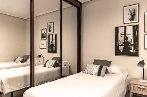 a bedroom with two beds and a mirror at AkomodaT en apartamento en el centro de Bilbao con parking in Bilbao