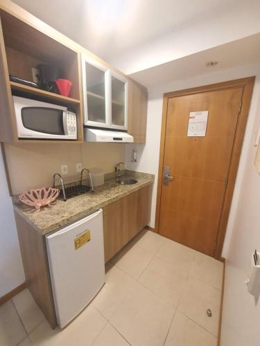 a small kitchen with a sink and a microwave at Flat Saint Moritz Express By Rei dos Flats in Brasilia